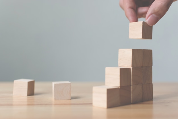 Mano che organizza l'impilamento del blocco di legno come gradino. percorso di carriera ladder