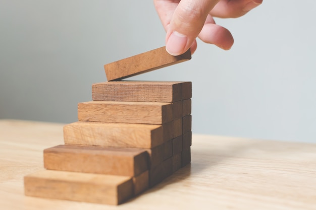 Hand arranging wood block stacking as step stair.