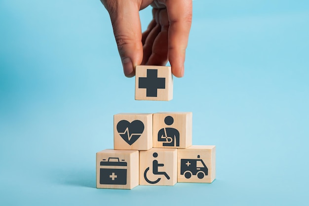 Hand arranging wood block stacking with the healthcare medical icon. Health insurance - health concept.