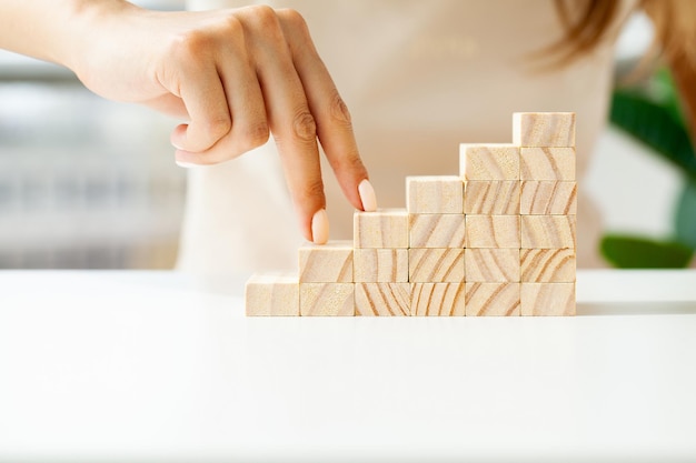 Hand arranging wood cube stacking as stair step shape