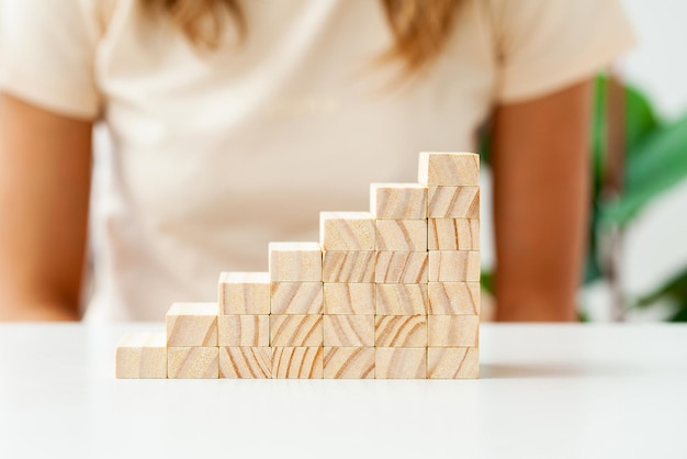 Hand arranging wood cube stacking as step stair