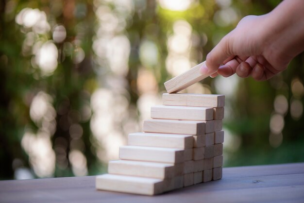 Mano che organizza blocco di legno che impila come punto su fondo rotto