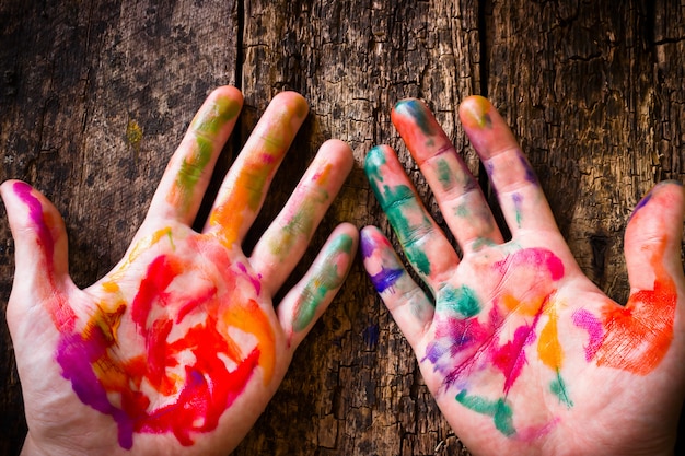 Photo the hand of the artist in stained colored watercolor paint on of a wooden table