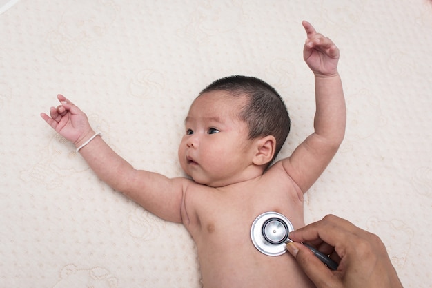 Hand arts examens baby met stethoscoop, kinderarts onderzoekt twee maanden pasgeboren Aziatisch meisje