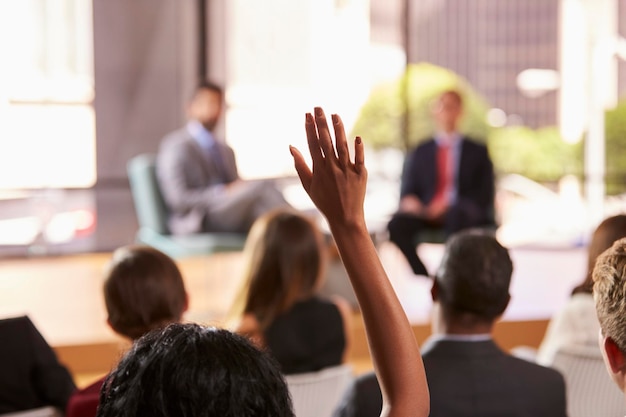 Hand in audience raised for a question at a business seminar