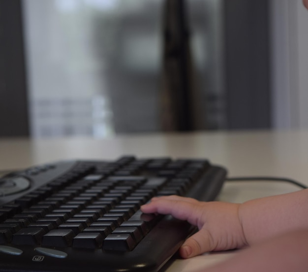 Hand of a baby with the computer keyboard