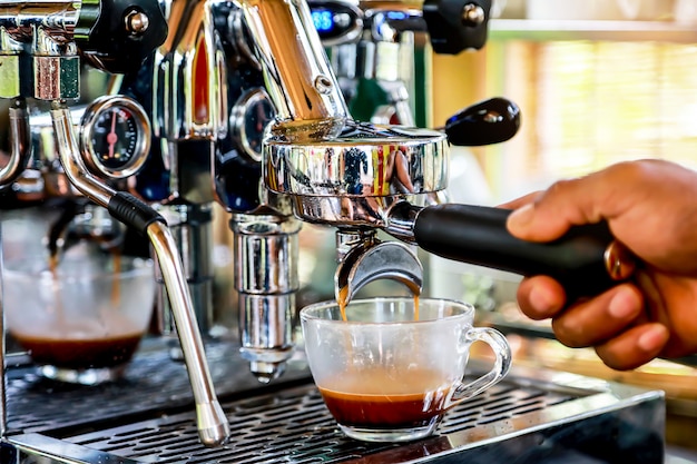 Hand of Barista making espresso coffee with the coffee machine in the coffee shop.