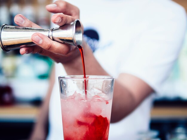 Hand of barman pouring alcoholic drink in cocktail