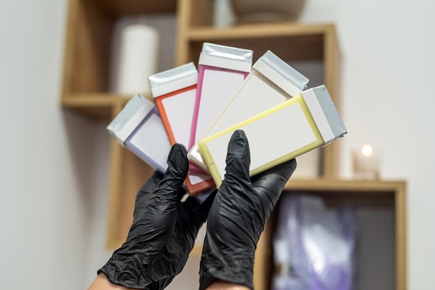 Hand of a beautician holding fatsoluble wax cartridges for hair removal