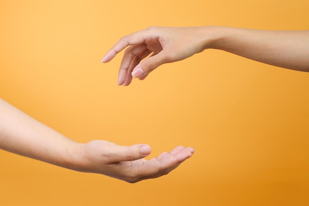 Hand bereikt een andere hand om te helpen geïsoleerd over gele achtergrond