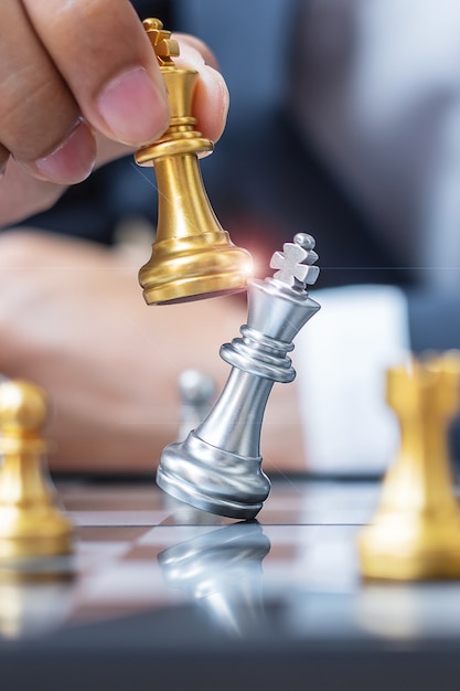 hand bewegende gouden schaakkoningfiguur tijdens schaakbordcompetitieboard