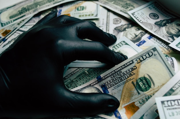 A hand in a black glove holds dollar bills