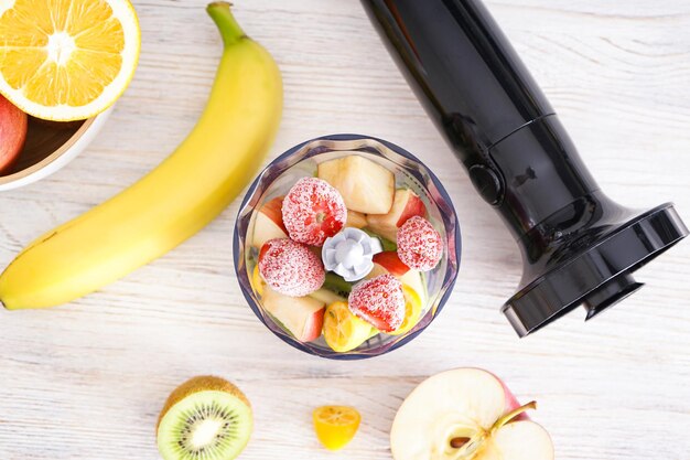 Hand blender and ripe fruit table at home cooking, top view.