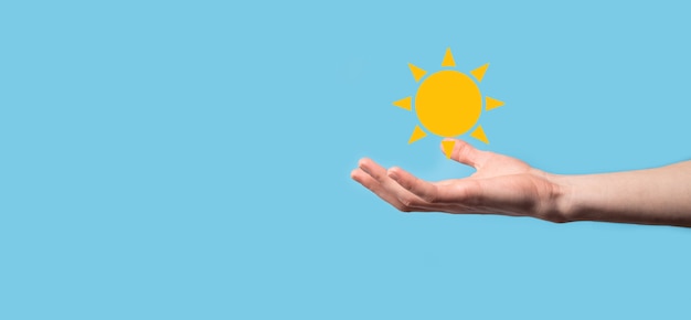 Рука на синем фоне держит символ значок солнца. Устойчивый источник электроэнергии, концепция электропитания. Эко экологически чистый технологический подход.