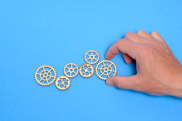 Photo hand on blue background lays a gear concept industrial progress