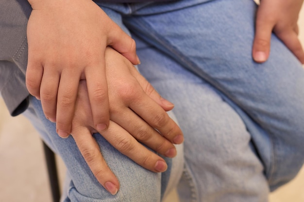 hand in blue denim sleeve holding child hand