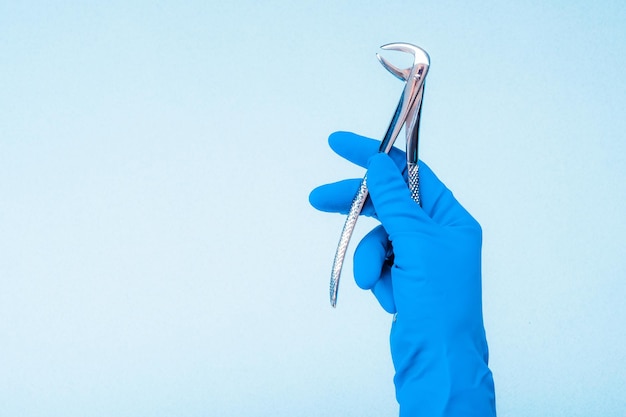 Hand in blue glove holding dental flatterns on light blue background