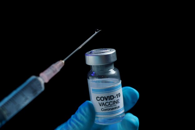 코로나 바이러스 감염 예방, 예방 접종 및 치료를 위해 백신 및 주사기 주사를 들고 파란 장갑에 손을.
