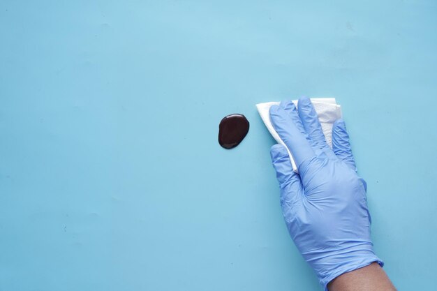 Hand in blue rubber gloves cleaning table with cloth