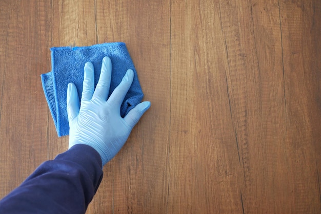 布でテーブルを掃除する青いゴム手袋をはめた手