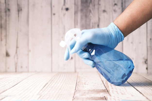 Photo hand in blue rubber gloves holding spray bottle cleaning table