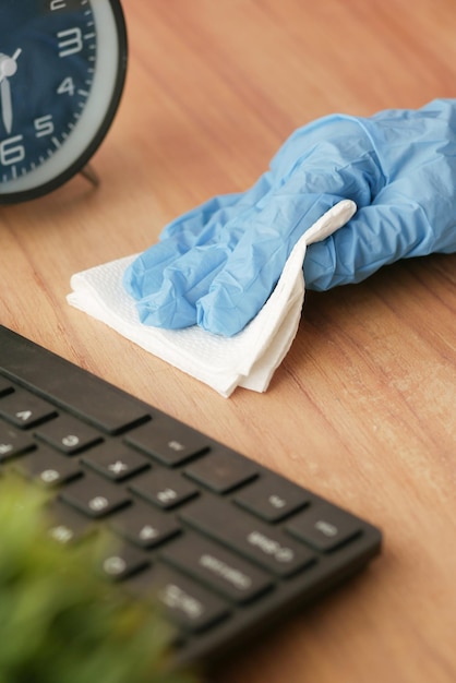 Hand in blue rubber gloves holding spray bottle cleaning table