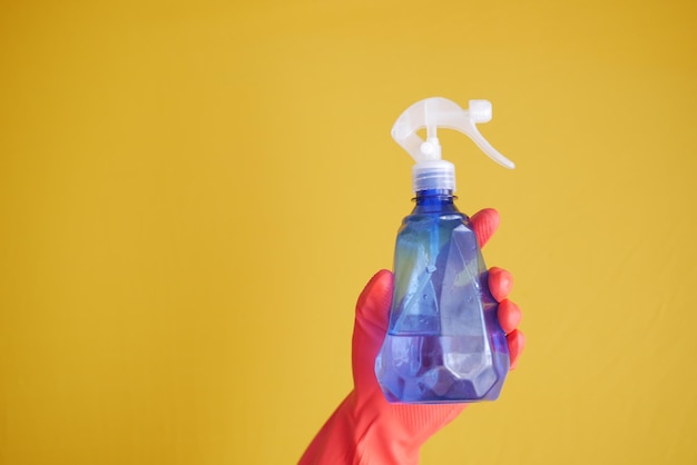 Hand in blue rubber gloves holding spray bottle with copy space