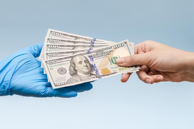 A hand in blue surgica glove takes the money dollars corruption in medicine field Corruption