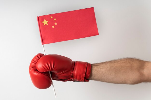 Hand in boxing glove holds the flag of China. Isolated on white background.