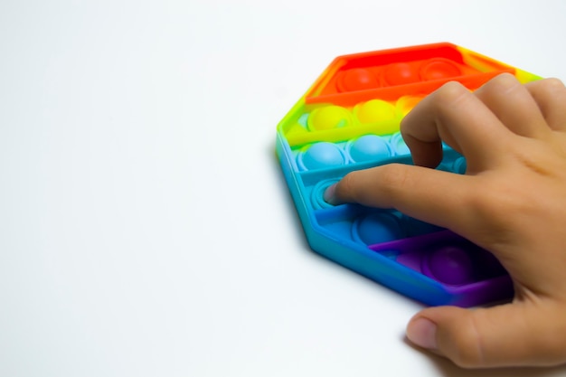 The hand of a boy with a pop it on a white background the development of fine motor skills