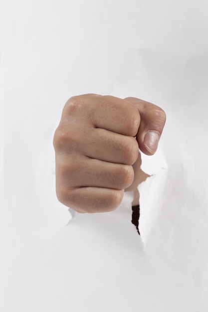 Hand breaking through a hole in a paper