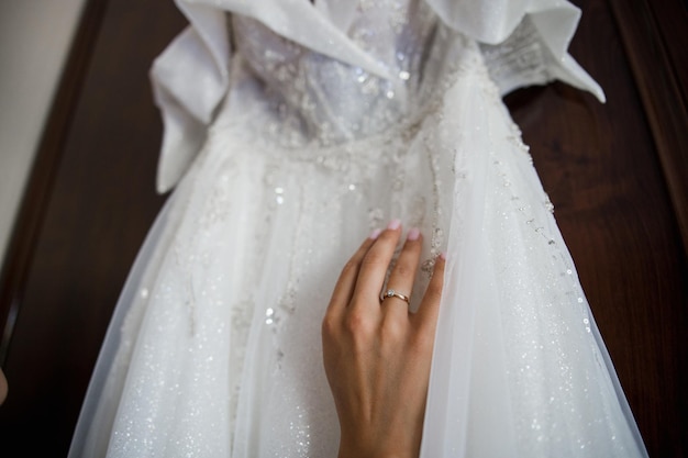 Hand of bride with ring on wedding dress