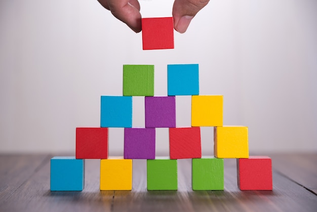 Hand building Colorful stack of wood cube blocks