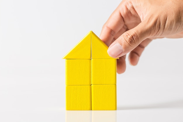 Hand building house (real estate) with wooden blocks