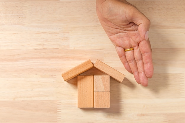 Hand building house (real estate) with wooden blocks