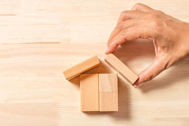 Casa della costruzione della mano con i blocchi di legno