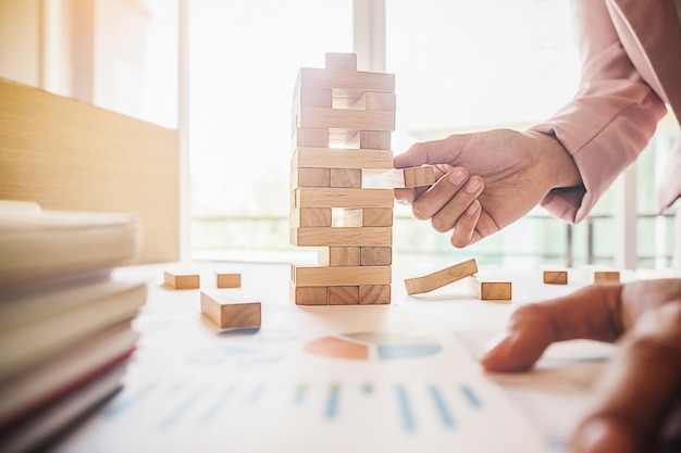 Mano dell'uomo di affari pianificazione, rischio e strategia nel business.businessman gioco che mette blocco di legno su una torre.