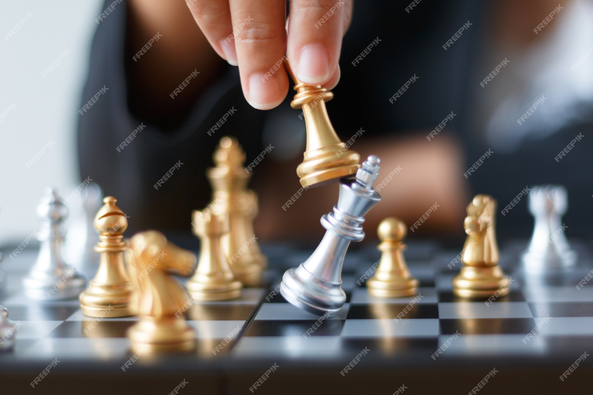 Concept: the woman who dominates the man. A woman's hand gives checkmate to  the king with the queen on a wooden chessboard, with no other pieces in  play Stock Photo