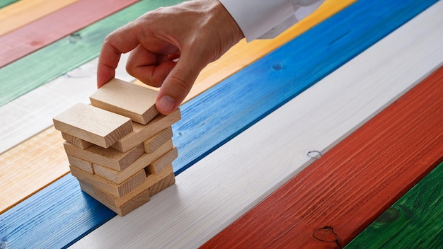 Hand of a businessman building a stack of wooden pegs