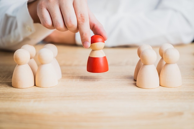 Photo hand of businessman choose and protect red wooden figure from group