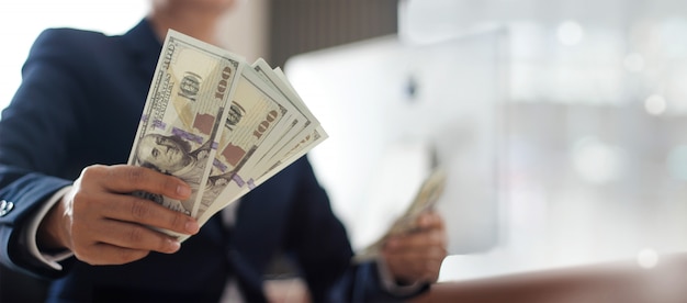 Hand of businessman holding banknote in office.