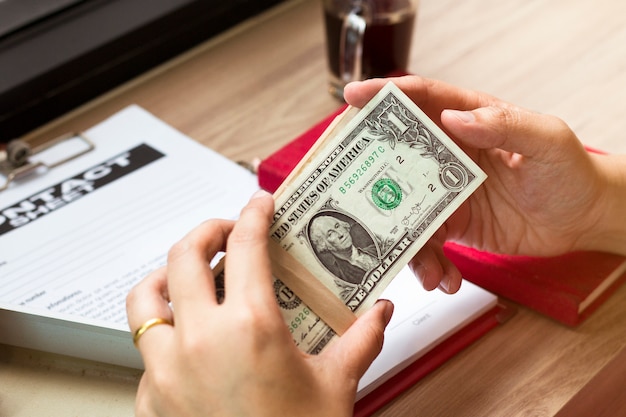 Hand of businessman holding dollar bill near business document