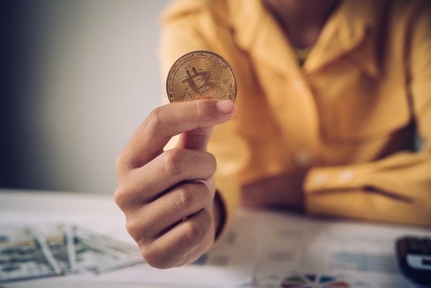 Mano di un uomo d'affari che tiene un bitcoin d'oro