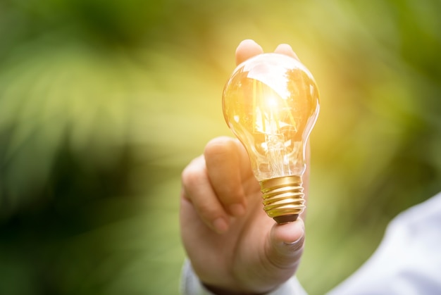 Hand of businessman holding illuminated light bulb, idea, innovation and inspiration conce