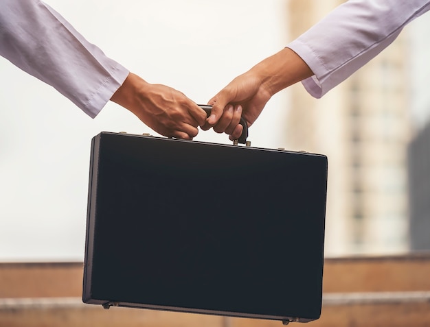 The hand of a businessman is exchanging a very important briefcase