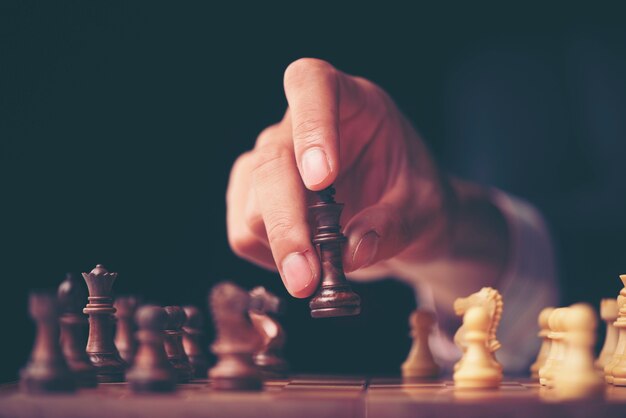 Hand of businessman moving chess figure in competition success play. strategy