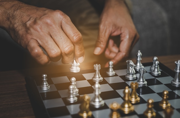 Hand of businessman playing chess assume making strategy management 