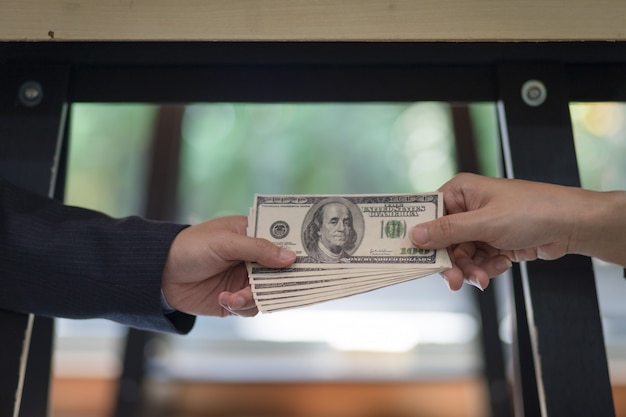 Photo hand businessman sealing the deal with a handshake and receiving a bribe money.