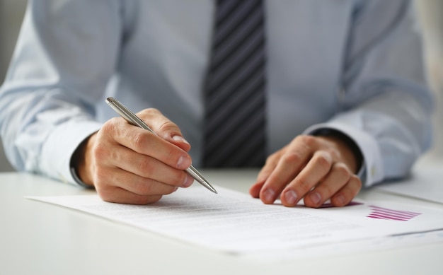 Hand of businessman in suit filling and signing with