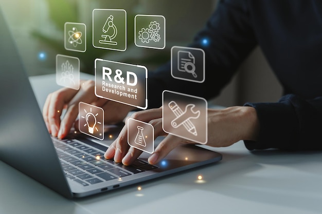 ノート パソコンの画面で研究開発の R と D のアイコンに取り組んでいるビジネスマンの手